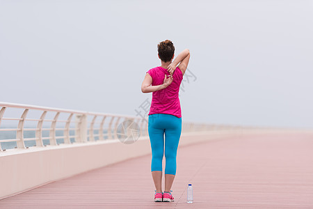 女人在赛道上伸展和升温海洋拉伸成人长廊女士热身慢跑者时间海滨微笑图片