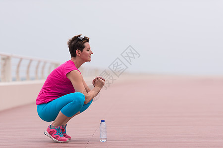 女人在赛道上伸展和升温训练跑步长廊女士海洋锻炼天空活动时间运动装图片