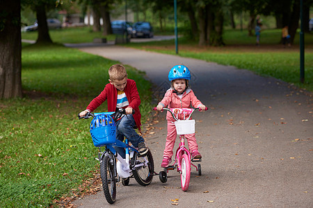 骑自行车的男童和女童乐趣赛车快乐行动家庭童年微笑孩子们朋友们姐姐图片
