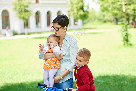 公园中快乐的年轻家庭婴儿儿子男生父母妈妈喜悦自行车女儿童年微笑图片