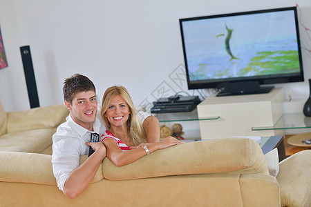 放松的年轻夫妇在家看电视男人妻子沙发娱乐电视女性女士技术长椅家庭图片