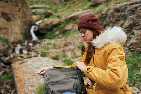 穿着黄色外套的女人 背着背包 在山上山区旅行冒险远足者风景女孩踪迹女性岩石旅游探索生态森林图片