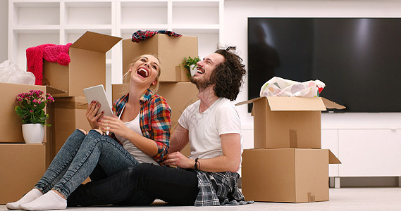 年轻夫妇搬进新房子搬迁微笑财产休息纸板拥抱公寓丈夫包装家庭图片
