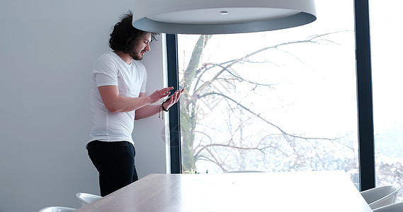 青年男子在家里使用平板电脑房间男生软垫房子男性技术冲浪快乐触摸屏成人图片