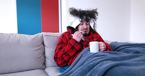 生病的人坐在沙发上 拿着杯子 坐在床上流感药品支气管炎男性疾病咳嗽传染性房间诊断鼻子图片