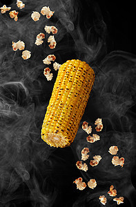 玉米和爆米花在黑底烟雾中徘徊图片