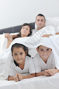幸福的年轻家庭在他们的卧室中孩子快乐男生父亲男性夫妻女士成人妈妈女性图片
