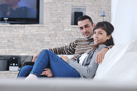 放松的年轻夫妇在家看电视喜悦电视丈夫沙发长椅家庭微笑妻子闲暇男性图片