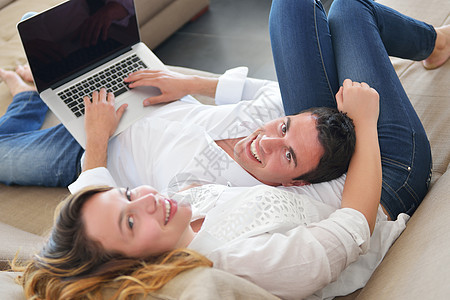 在家使用笔记本电脑的年轻夫妇闲暇成人互联网丈夫生活女士妻子房间阅读微笑图片
