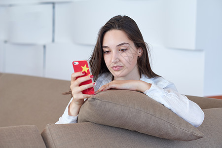 在家使用手机的年轻女性女孩白色房子生活黑发技术快乐细胞电话沙发图片