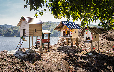 传统泰国微型木制木制房屋建在大坝的岩石边缘上 并有三座建筑宗教庙宇村庄灵魂废料风景文化艺术石头房子图片