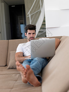 用笔记本电脑在索法放松的人男人男性长椅财产水平纸板技术房子房地产微笑图片