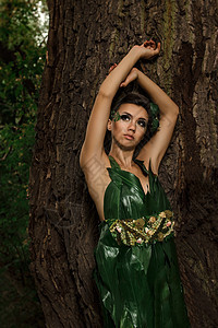 身着绿棕榈树的女子树叶姿势棕榈森林时尚黑发裙子绿色花朵背景图片