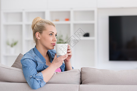 女人喜欢喝一杯咖啡成人沙发香气乐趣女士享受女孩微笑房子公寓图片
