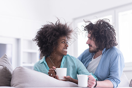 坐在沙发上在家喝咖啡的多民族夫妇男人妻子成人微笑房间男性黑色女孩女性女朋友图片