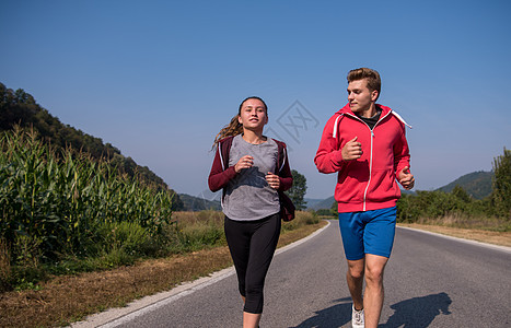 在乡村公路上慢跑的年轻夫妇阳光活动运动员冒险自由运动女孩农村国家女性图片