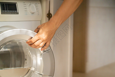 男人正在使用现代洗衣服晴天机器烘干机房间房子洗衣机家庭男性垫圈服务图片