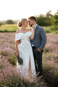在熏衣草地上的新娘和新郎男朋友植物白色夫妻蓝色套装地面场地婚礼散步图片
