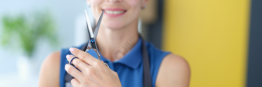 戴眼镜的女理发师将专业金属剪刀握在手上图片