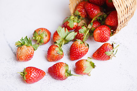 以篮子和白色背景的新鲜草莓 以自然背景的红色成熟草莓图片