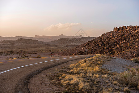 在日落的犹他州沙漠公路 原始的岩石景观 美国犹他州背景