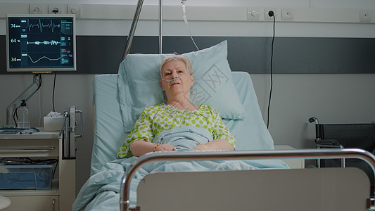 坐在医院病房床上治疗疾病的老年妇女的肖像;病历图片