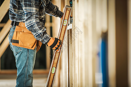 承包商工人使用水平仪工具确保木框对齐正确 施工工具和建筑技术图片