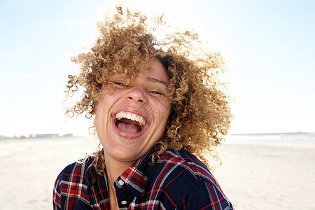 紧贴着快乐的非洲年轻美国女人 在海滩上大笑图片