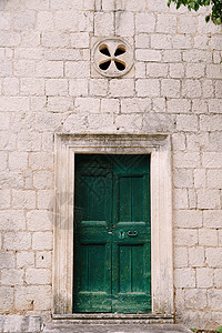 绿色木制门 在大楼的石面墙上拉起手柄图片