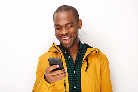 在孤立的白色背景下看着手机 笑着笑着的年轻黑人男子图片
