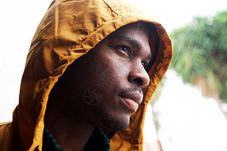 年轻黑人在雨淋雨 雨衣和雨衣的户外背景图片
