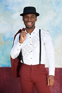 穿着旧西装和帽子的英俊年轻黑人男子 在墙边微笑图片