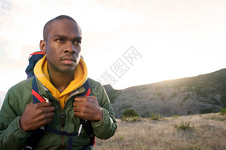 早起带着背包在山上行走的年轻黑人男子图片