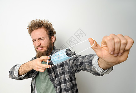 脱下保护性医疗面罩 蒙住年轻英俊男子的面罩 将面具拉在脸前 身着格子衬衫和橄榄T恤疾病药品白色呼吸流感成人商业男性人士黑色图片