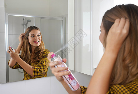 年轻漂亮的女人在她的头发上涂抹干洗香波 使用干洗洗发水保持头发清洁的快速简便方法图片