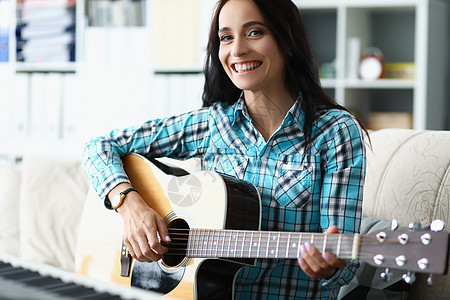快乐的年轻女子在家里客厅弹吉他女性火车钢琴微笑音乐家歌曲学习音乐笔记喜悦图片