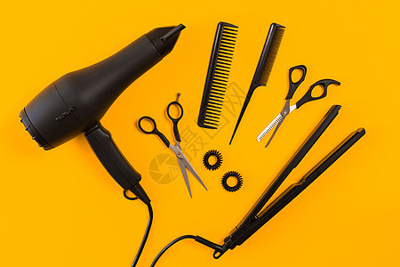 黄色纸面背景的黑吹毛机 梳子和剪刀沙龙鼓风机发型师发型设计平铺理发师工具头发烘干机吹风机图片