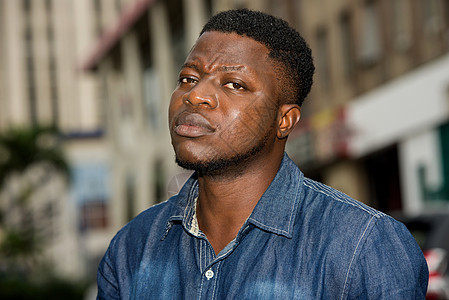 年轻非洲男子的肖像情感嘴唇黑色牛仔裤按钮男生市中心男性愤怒褶边图片
