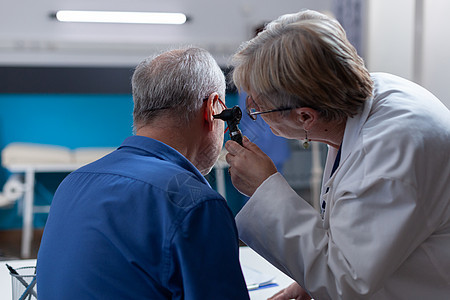 持有眼镜的医生为病人进行检查探视时做耳腔咨询图片