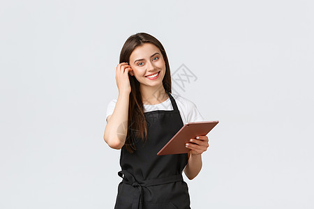 Grocery商店雇员 小企业和咖啡店概念 友好而可爱的黑围裙女女酒吧员在照相机上微笑 用数字平板电脑管理咖啡店订单机器购物客户图片