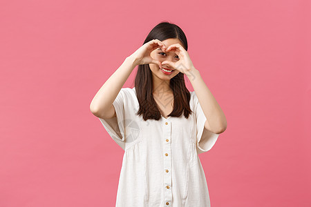 美丽 人们的情感和夏季休闲概念 可爱 浪漫 害羞的亚洲女孩 穿着白色裙子 像某人一样 表达同情或爱意 在粉红色背景中表现出心脏标图片
