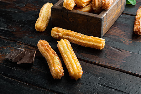 典型的西班牙零食churros 炸面糕饼通常配巧克力焦糖热辣酱 在旧黑木桌背景上油条油炸木质糕点桌子美食早餐烹饪饼干文化图片