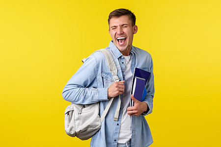 教育 课程和大学概念 快乐帅气的男学生在校园里享受生活 背着背包和学习材料 笑着笑着兴奋 黄色背景图片