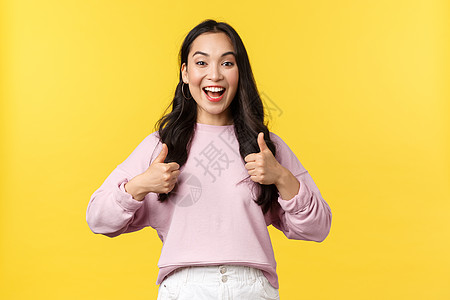 人们的情感 生活方式和时尚理念 雄心勃勃 兴奋的微笑亚洲女性竖起大拇指表示赞同 同意或支持好主意 祝贺或赞美朋友 黄色背景图片