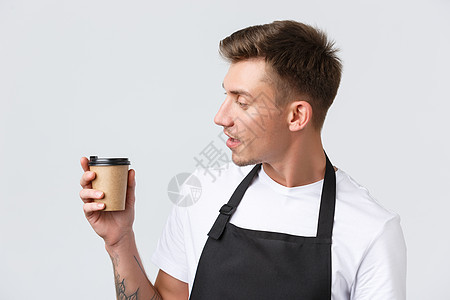 咖啡馆和餐馆 咖啡店老板和零售概念 友好帅气的咖啡师特写 看着纸杯加卡布奇诺 递交订单 站在白色背景图片
