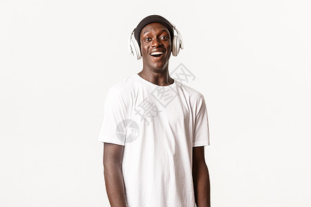 欢笑和快乐的非洲-美国年轻人的肖像 他们用耳机 微笑的喜悦和白背景播放播客或音乐图片