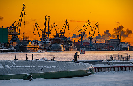 神奇日落时建造核破冰船 寒冷冬日波罗的海造船厂的起重机 涅瓦河上的蒸汽 光滑的河面 橙色的天空港口货轮运输送货城市血管出口建设码图片