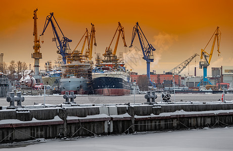 神奇日落时建造核破冰船 寒冷冬日波罗的海造船厂的起重机 涅瓦河上的蒸汽 光滑的河面 橙色的天空机器渔船血管货物技术霜天港口出口船图片