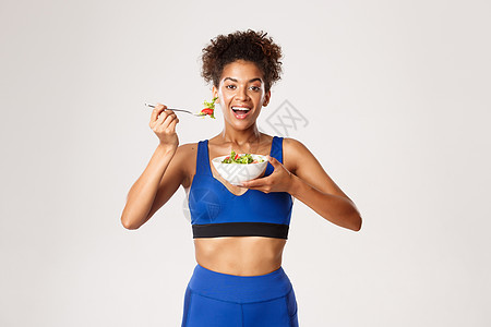 健康的生活方式和体育概念 美丽的非洲-美国健身女子 穿着运动服装 在吃沙拉和微笑中站立图片