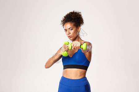 坚定的非洲美国健身妇女 拳击 用哑铃打练拳 站在白种背景下站立在运动和锻炼的概念衣服广告动机耐力身体活力训练皮肤瑜伽情感图片